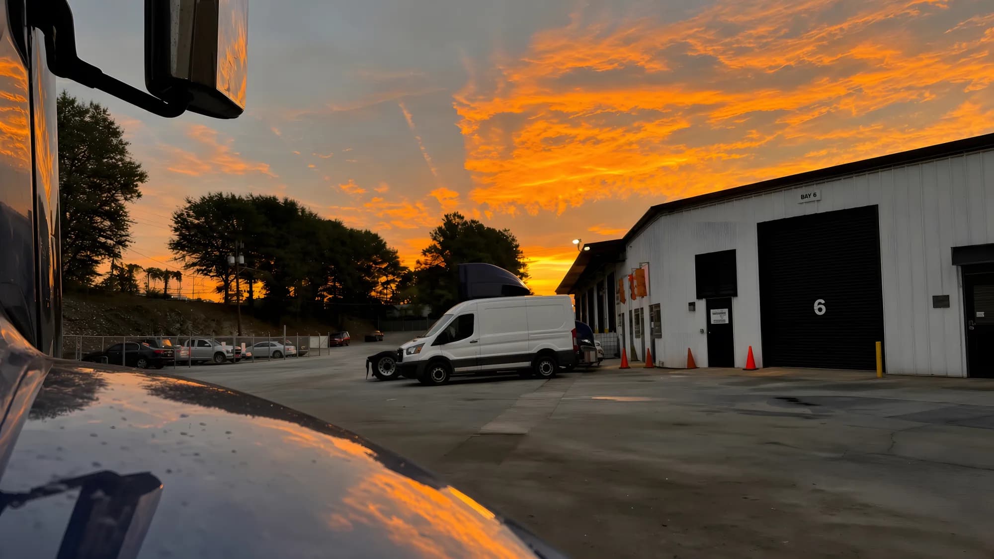 Service yard at dawn with a van staged outside the bay doors.