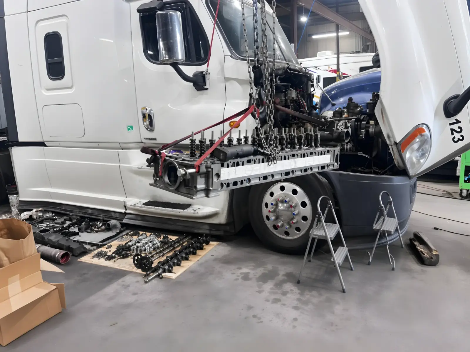 Sleeper tractor with the hood removed and engine harness laid out for repair.
